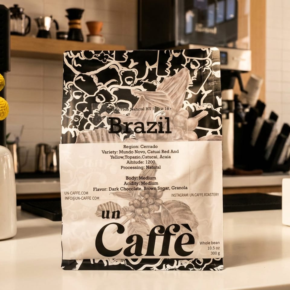 Brazilian whole-bean coffee bag displayed on a café counter beside white vases and brewing equipment.